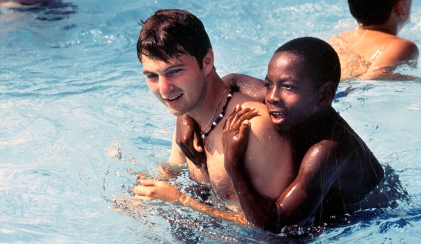 Neil Willenson, swims at Camp Heartland with young boy.