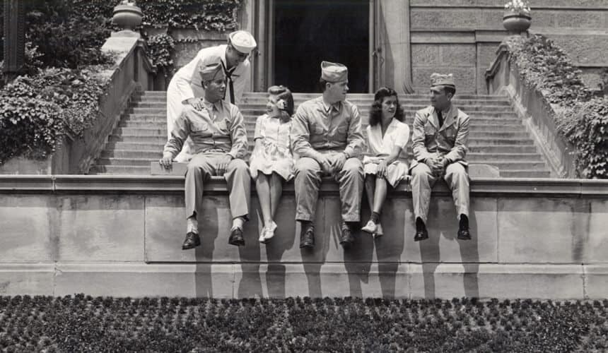 World War II-era military trainees sit in front of the Union with female students.
