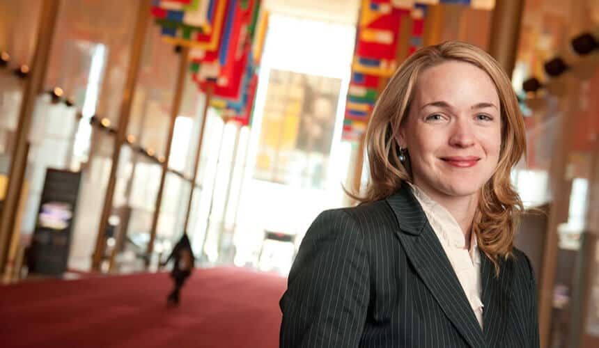 Caroline Savage in a hallway with flags of different nations hanging from above.