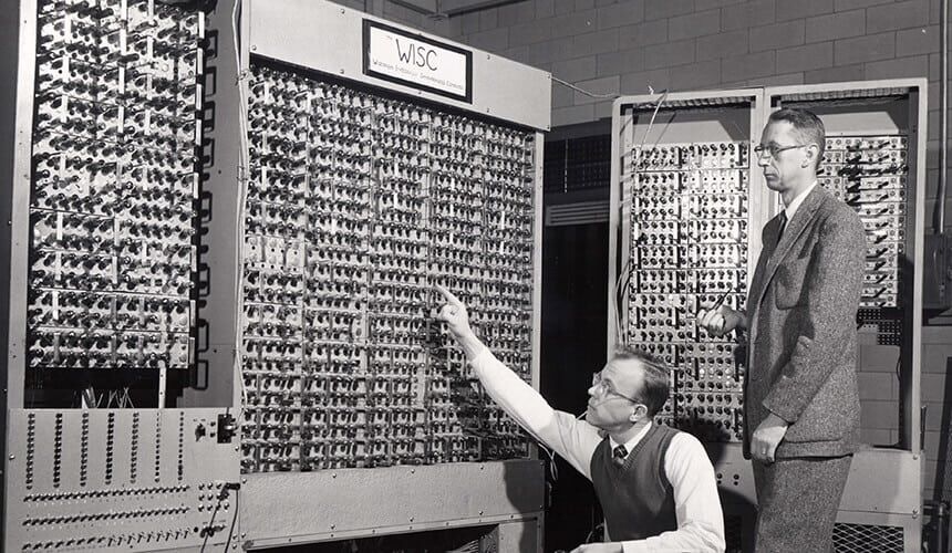A front view of the Wisconsin Integrally Synchronized Computer (WISC). Professor Allan Scidmore (kneeling) and professor Charles Davidson scrutinize one of the assemblies of 1,500 electronic tubes at the College of Engineering.