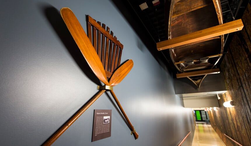 A vintage canoe and paddles from the first-ever Hoofers trip hangs above a hallway corridor leading to Outdoor UW at the Memorial Union. (Image courtesy of University Communications, #5969. Photo by Jeff Miller.) Vintage canoe and paddles