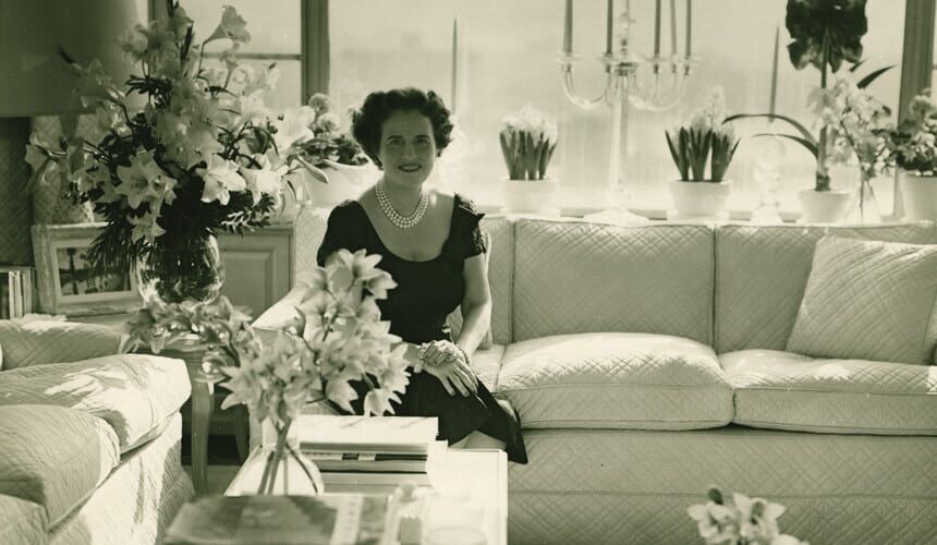 Mary Lasker sitting on a couch surrounded by flowers. (Image courtesy of the NIH.) Mary Lasker sitting on a couch surrouned by flowers.