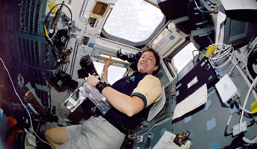 Clark holding a camera while floating onboard the Columbia spacecraft.