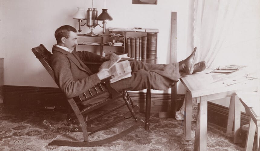 Edward Schildhauer sits in a rocking chair at an angled architect desk.