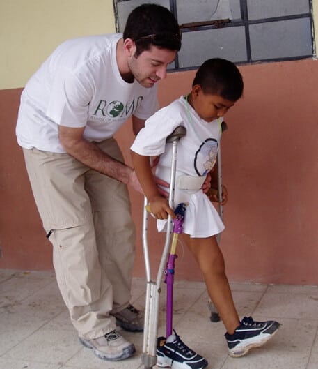 Eric Neufeld helping a child walk with new prosthetic limb.
