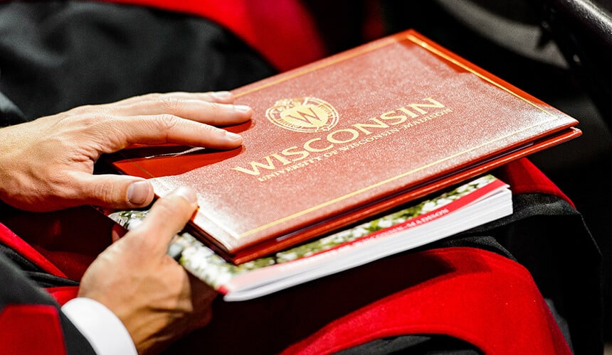 A just graduated student holding onto their diploma. (Image courtesy of University Communications.)
