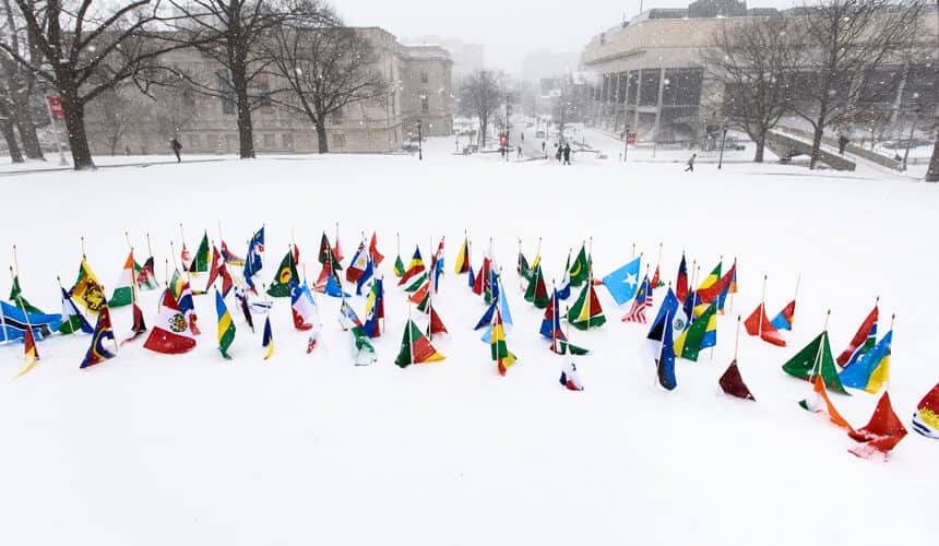 International flags planted in the snow on Bascom Hill.